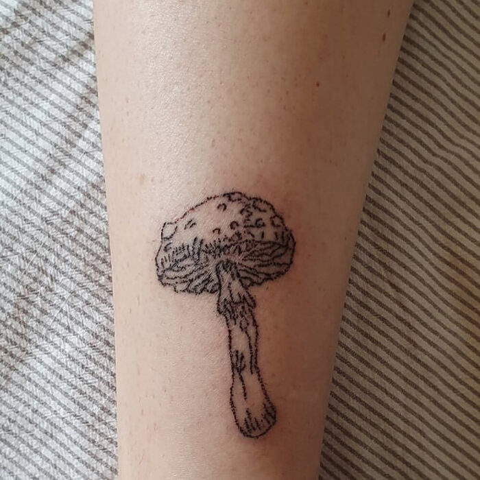 Hand poke tattoo of a mushroom