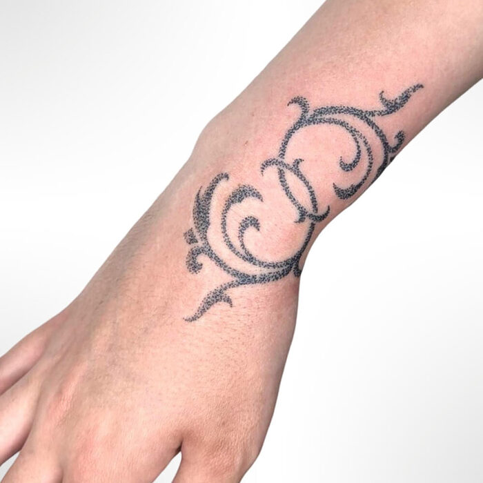 Stick and poke tattoo of swirls on a wrist